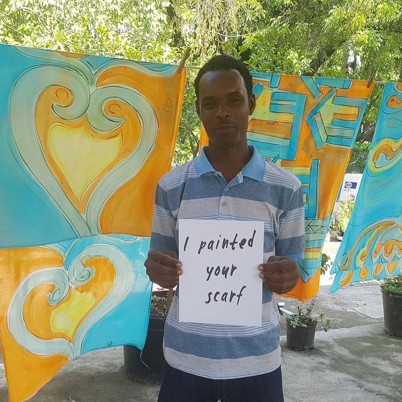 Peintre de Sandilou devant des foulards peints de cœurs orange et turquoiseSandilou